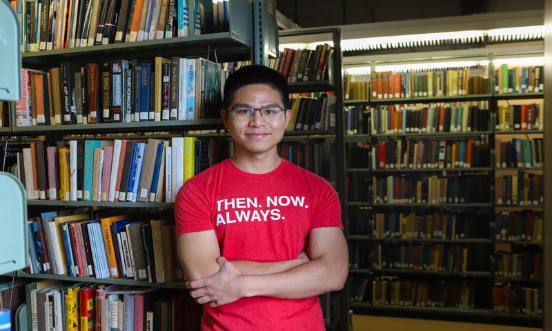 a man standing in front of a shelf of books